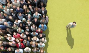 Young man standing to the side of a large crowd